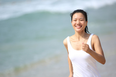 健康的运动女人在海边沙滩上跑步