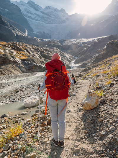徒步旅行运动的女人背着背包和登山杆在高山。