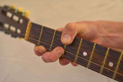 男人的手在弹古老的原声吉他。旧吉他头与调音栓。