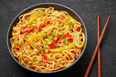 辣椒蒜味客家面在黑色的碗里，在黑色的石板桌上。印中素食菜肴。印度蔬菜面条。典型的亚洲餐