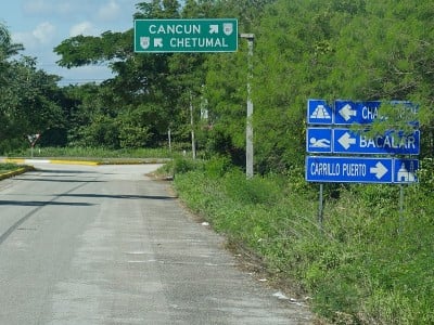 铺设道路和十字路口的方向标志，以坎昆和切图马尔，墨西哥和其他目的地。