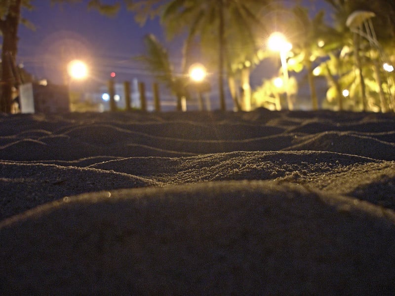 夜景拉近了沙波起伏，沙滩和模糊的城市街灯景观