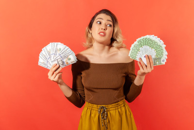 惊讶的女商人捧着粉丝的美元和欧元钞票，汇率，支付服务