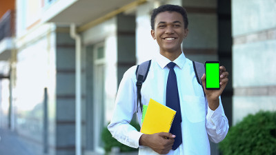 开朗的混血儿男学生，课本上显示着绿色屏幕的手机