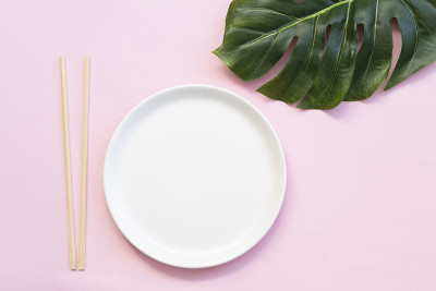 粉红色背景上的空盘子和寿司筷子