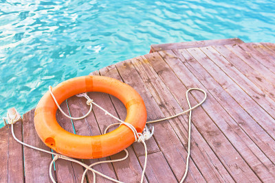 Orange lifebuoy with rope on a wooden pier near se