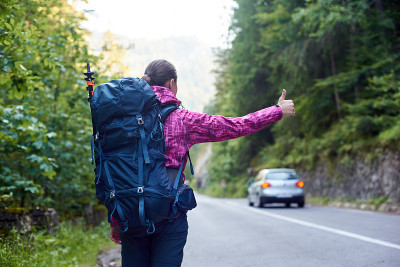 一名女性背包旅行者在罗马尼亚比卡兹峡谷的路上追赶一辆汽车