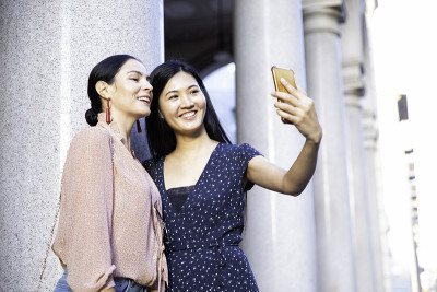 快乐的中国亚洲女友在户外玩手机