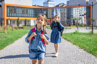 小女孩，小学生背着书包离开学校。