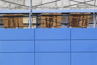 在建购物中心靠墙的金属脚手架。建筑施工理念，外墙装饰采用蓝色通风立面。