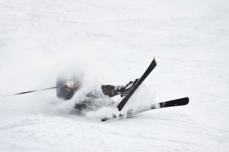 一个滑雪者踩着滑雪板掉在雪地里