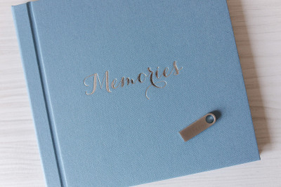 Blue textile photobook on white wooden table. Clos