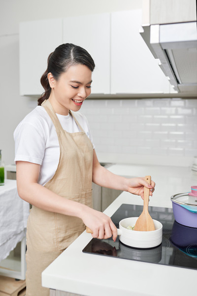 在厨房里用木勺做饭的女人