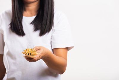 女人头发弱，她显示发刷受损长脱落的头发在梳子刷的手上