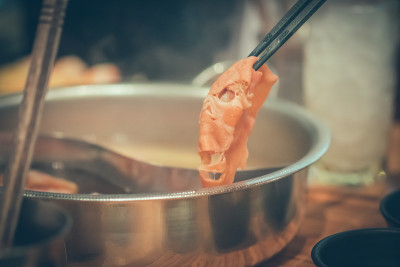 手握猪肉用筷子在火锅与烟日式火锅