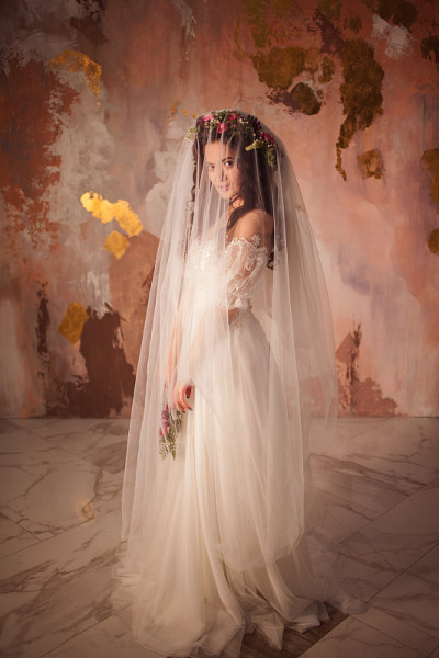 美丽的年轻新娘穿着婚纱，脸上戴着面纱