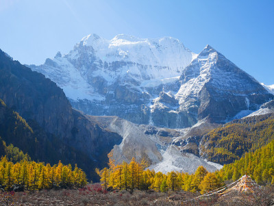 在亚丁自然保护区，白雪覆盖的山峰上有五颜六色的秋叶