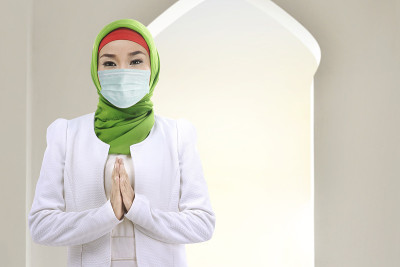 亚洲穆斯林妇女戴着面纱和口罩祈祷
