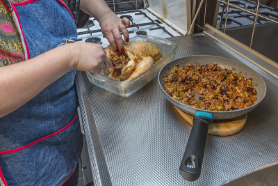 想象一下，一个女人正在用用橄榄和葡萄干准备的碎肉填满新鲜的生鸡肉