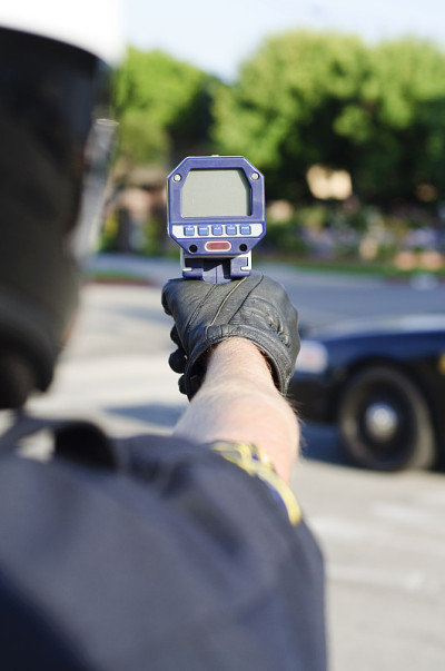 一名警察拿着雷达枪指着街道