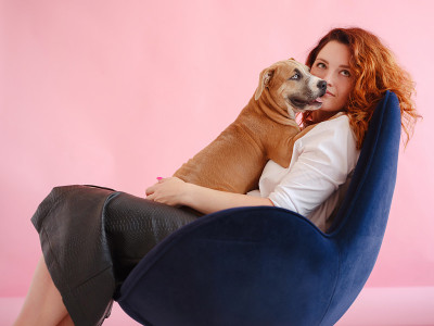 一名女子带着一只美国斯塔福德郡梗犬在摄影棚拍照