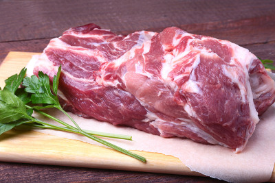 生猪颈剁肉和欧芹叶在石头背景上。准备做饭。