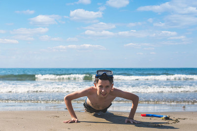 13岁的男孩在海滩上拧着潜水面罩和潜水管。旅游和夏季概念。
