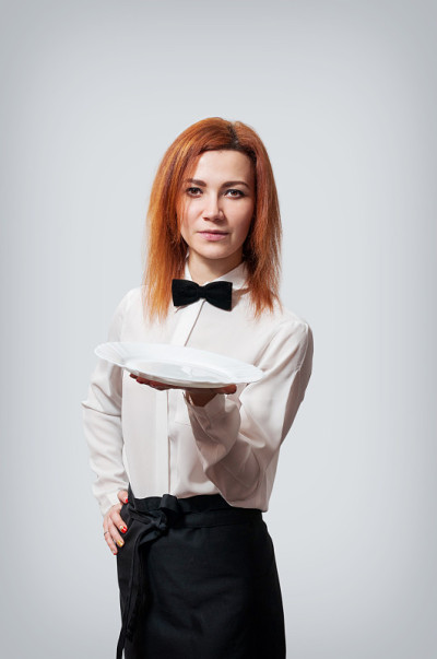 穿着服务员制服的年轻女子拿着盘子