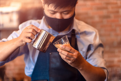 咖啡师制作卡布奇诺。为准备一杯咖啡倒牛奶。拿铁艺术。