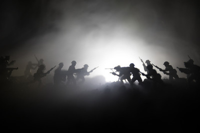 战争的概念。军事剪影战斗场景的战争雾天空背景，世界大战士兵的剪影下多云的天际线在晚上。攻击的场景。装