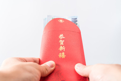 男人的手拿着中国的红包。中国新年的概念。(中文“Gōnghè xīnxǐ”的意思是“祝你财源广进”)