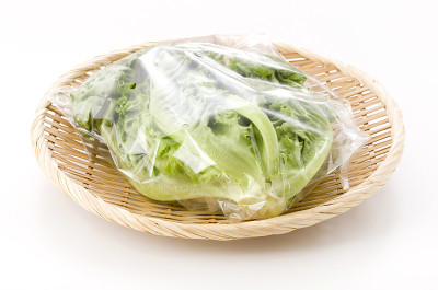 新鲜的绿叶生菜装在竹制滤锅上，白色背景，