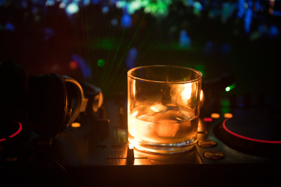在夜总会的dj控制器上，装有冰块的威士忌酒杯。Dj控制台与俱乐部饮料在音乐派对在夜总会迪斯科灯。
