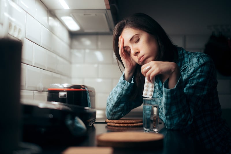 手持药片的妇女夜间疼痛