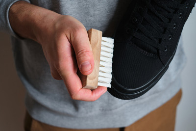 一个男人正在车间里清洗运动鞋。擦鞋服务服务。鞋匠准备应季的鞋子。鞋刷特写。鞋子护理用一种特殊的产品