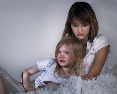姐姐孩子难过。抱着哭泣的小妹妹。孩子们在床上泪流满面