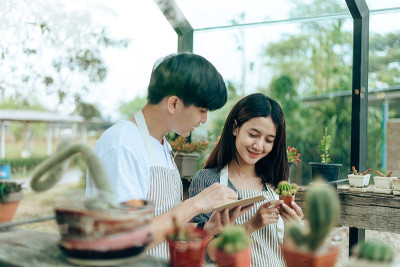 Women hold cactus and a man writing note in a book