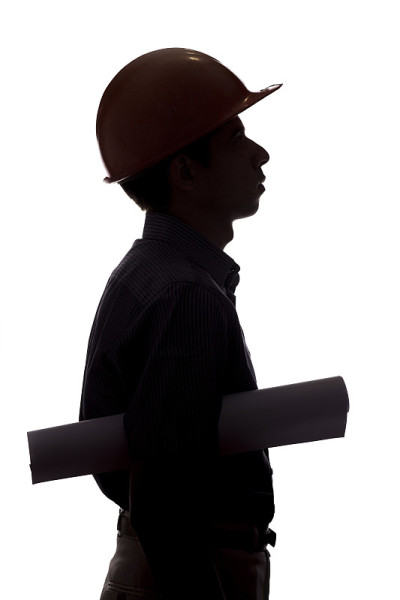建筑工人的剪影与项目在手中，男子在安全帽和安全眼镜在白色孤立的背景工作服