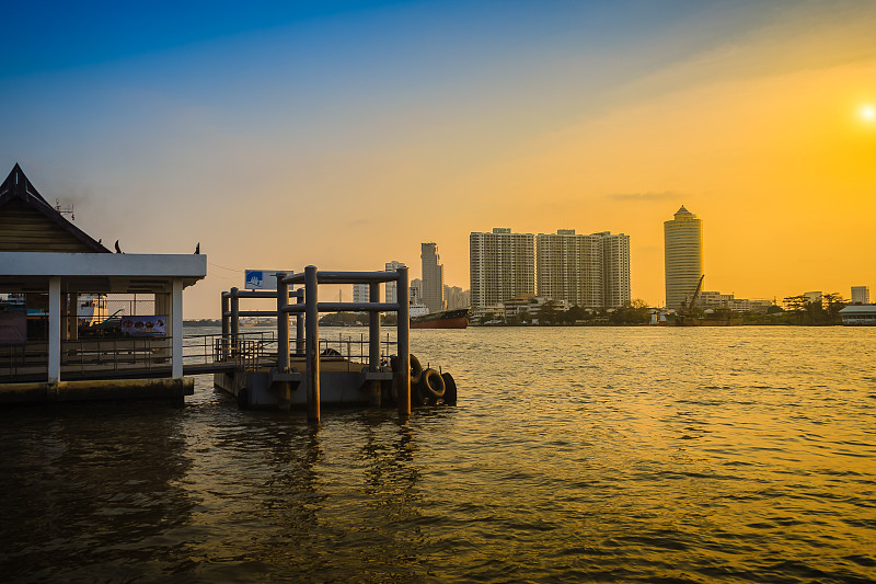 夕阳下的湄南河畔，高楼大厦和蓝天背景。泰国曼谷宁静的河堤。