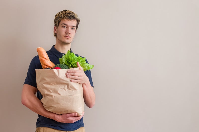 一个年轻人拿着一袋食品杂货