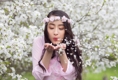 女孩在粉红色的奥黛吹白色的花瓣