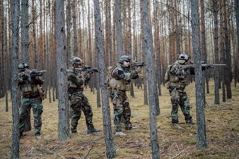 全副武装的士兵穿着迷彩服攻击敌人，步枪在射击位置。行动中的军事行动，小队在正午以队形穿过密林