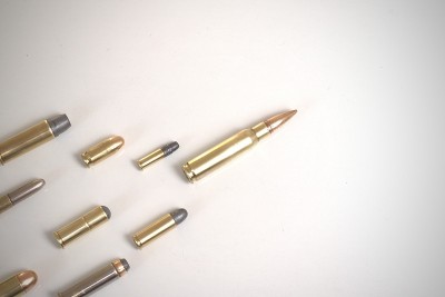 一颗大子弹(7.62 x51毫米北约)，在白色背景下作为其他各种口径子弹的领导者。