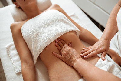 女按摩师在健康中心为女性客户按摩腹部