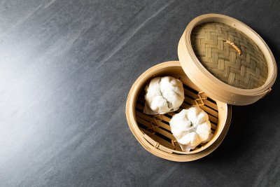 中国传统美食的概念。饺子点心在竹蒸笼内用文字抄写空间。亚洲食物背景
