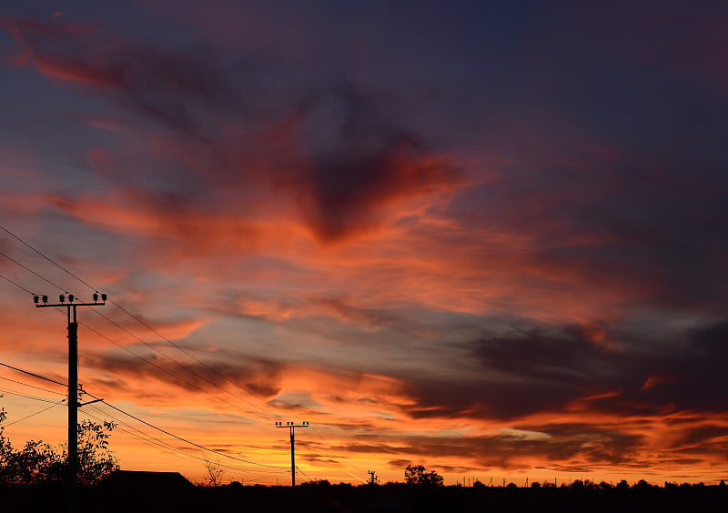 鲜红的夕阳。橙黄红色的天空背景和电线。夕阳色调色板