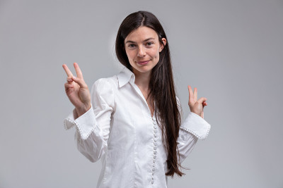 年轻的长头发妇女显示胜利的标志