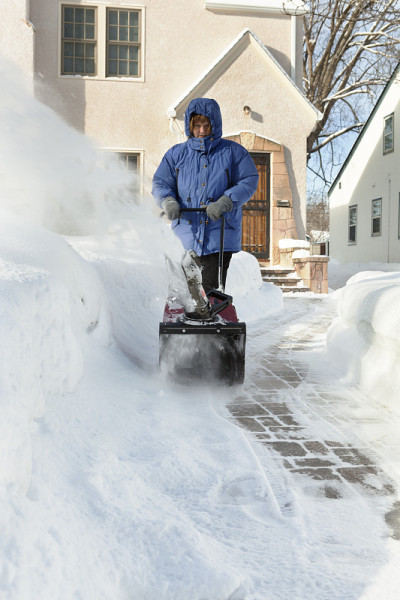 房主在房子前面吹冬天的雪
