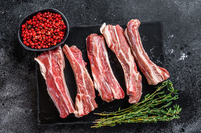 生小牛肉切成薄片，放在大理石板上。黑色背景。前视图。本空间