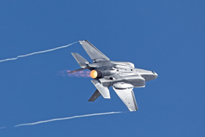 F-35闪电II在一个高g机动，加力燃烧器和凝结尾在机翼的尖端